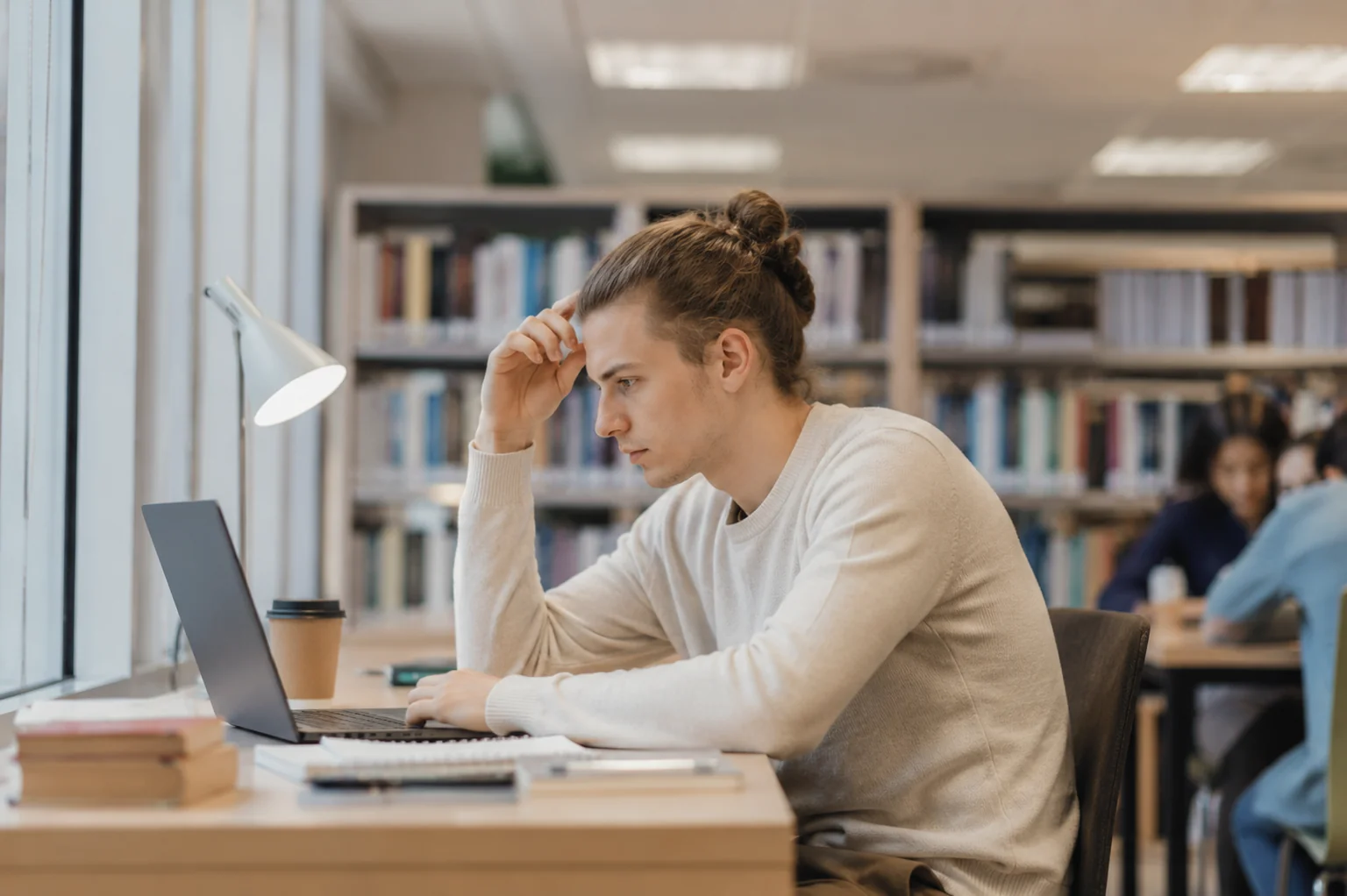 Lycéen concentré travaillant sur son ordinateur dans une bibliothèque